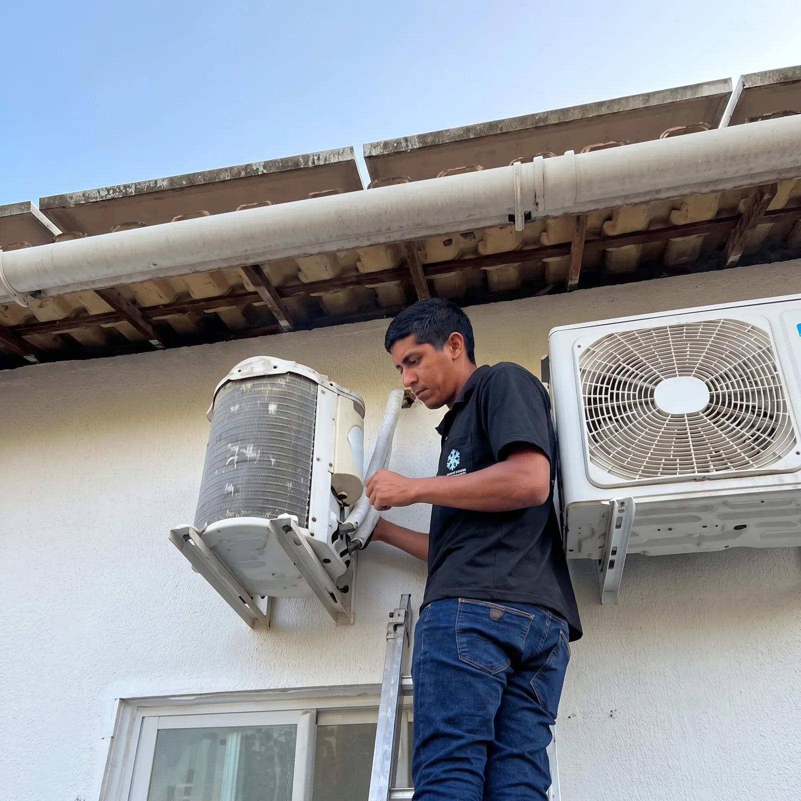 Técnico da Ideal Clima na escada, instalando a condensadora de um split na fachada de uma casa