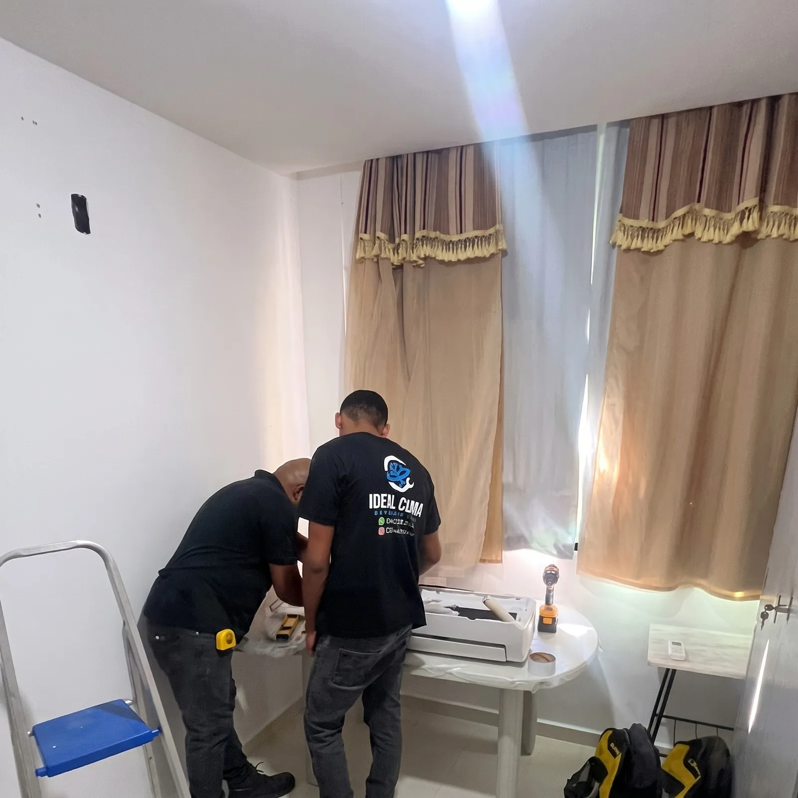 Dois técnicos da Ideal Clima preparando a instalação de um split em um quarto